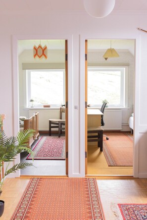 Una habitación con un ventanal grande, una silla, un escritorio y una planta en maceta.