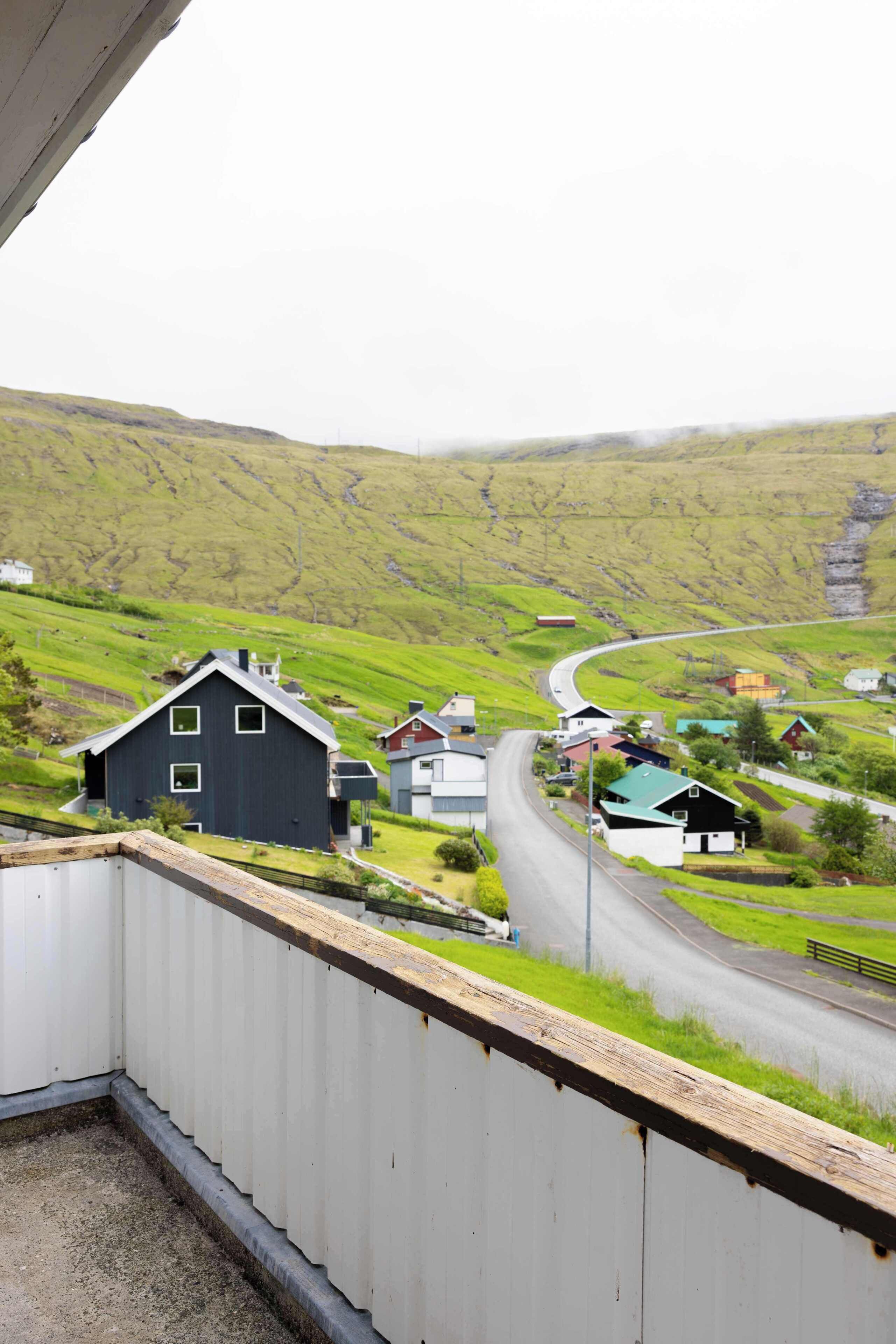 Un paysage rural avec une route sinueuse, des maisons et un bâtiment noir imposant.