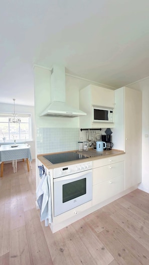A modern kitchen with a central island, built-in oven, microwave, and a hanging pot rack.