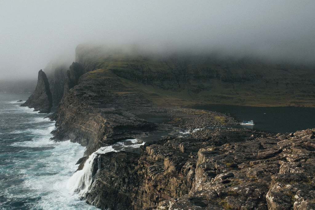 A coastal landscape with rocky cliffs, a body of water, and a boat.