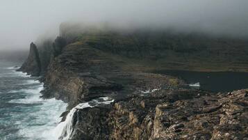 A coastal landscape with rocky cliffs, a body of water, and a boat.