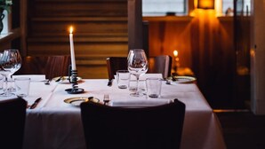 A dining table set with wine glasses, plates, and cutlery, with a candle on the table. - Adventure Autocamper Van to Explore the Faroes (Hoyvík)