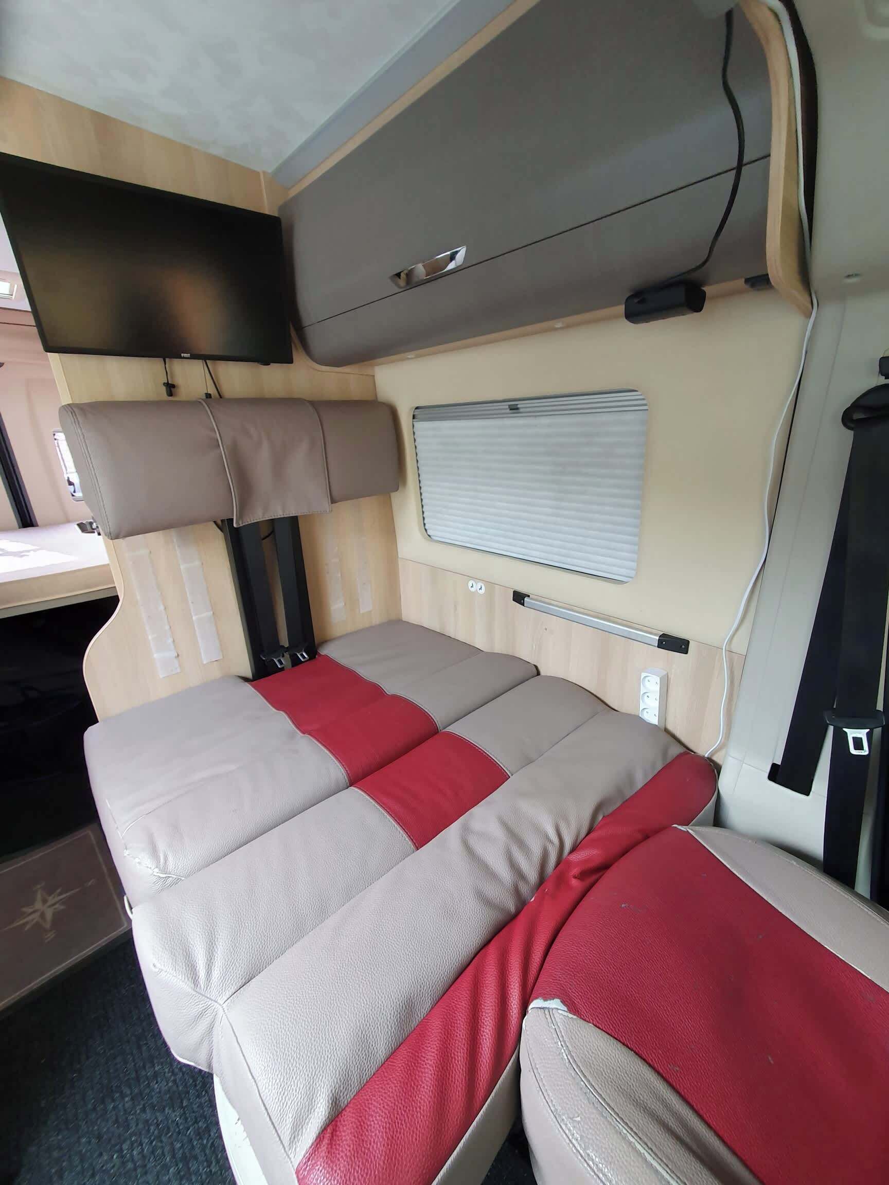 Un intérieur de camping-car compact comprenant un lit, une petite table et une fenêtre.