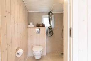 Une petite salle de bain avec des toilettes, une douche et une fenêtre.