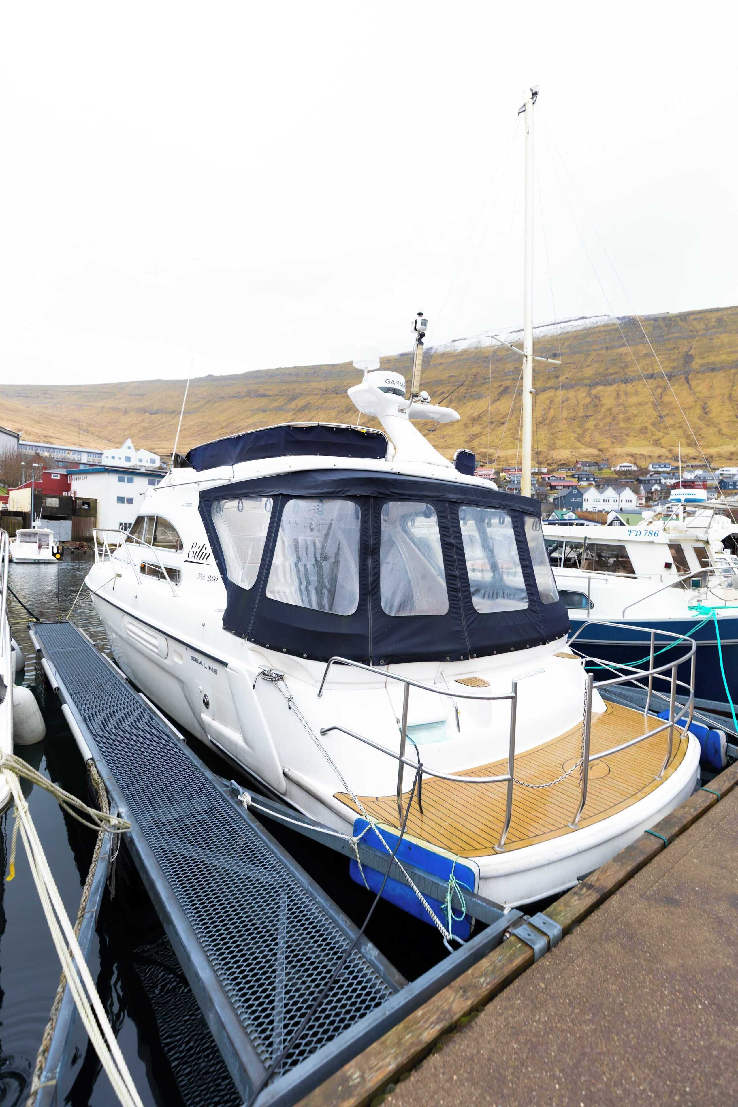 A white yacht docked at a marina with a covered deck and a cabin.