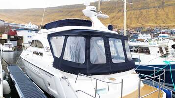 A white yacht docked at a marina with a covered deck and a cabin.