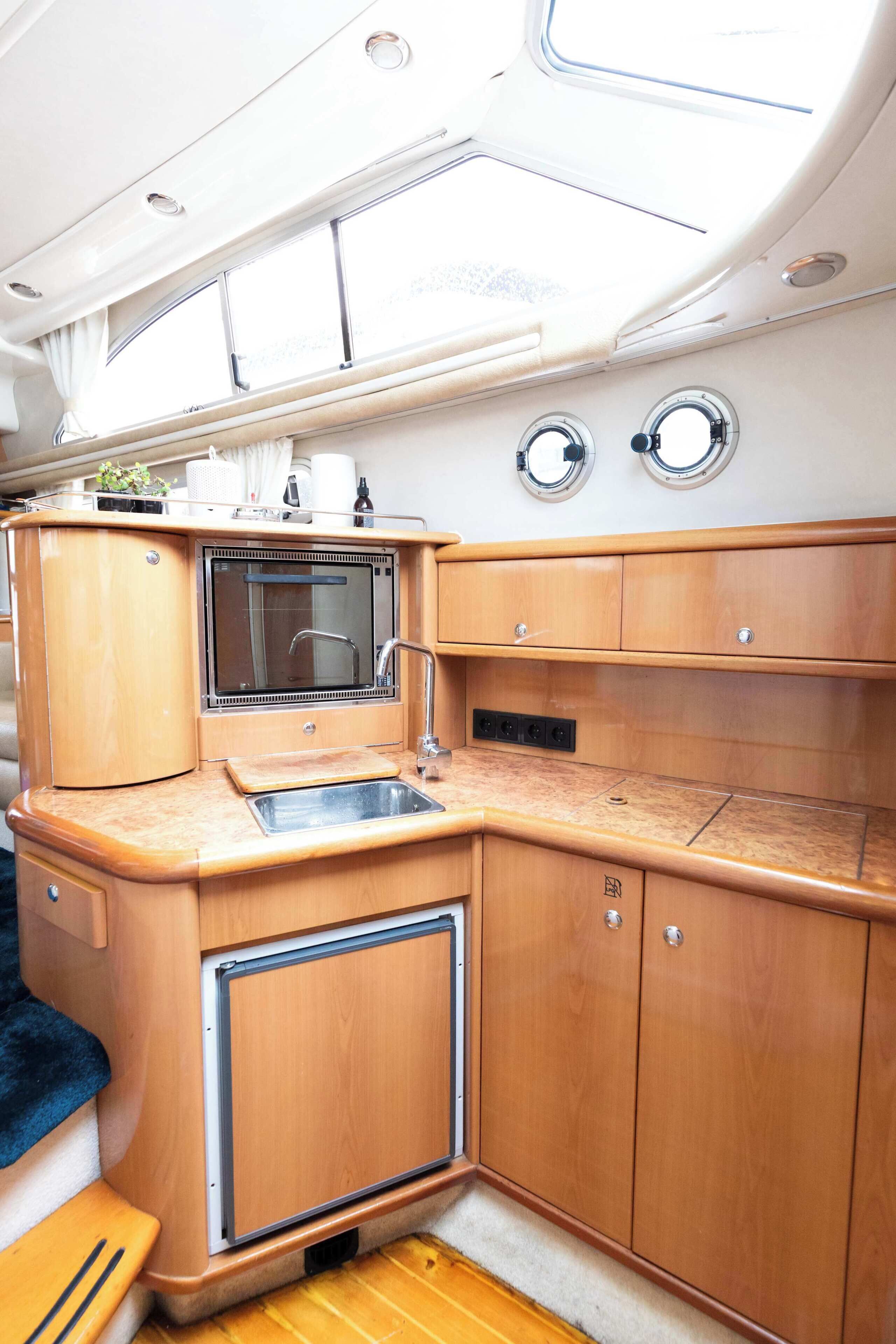 A compact galley with a sink, stove, and storage cabinets.