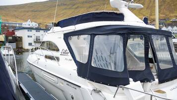 Un yate blanco amarrado en un puerto deportivo, con una cabina cubierta y camarote visible.