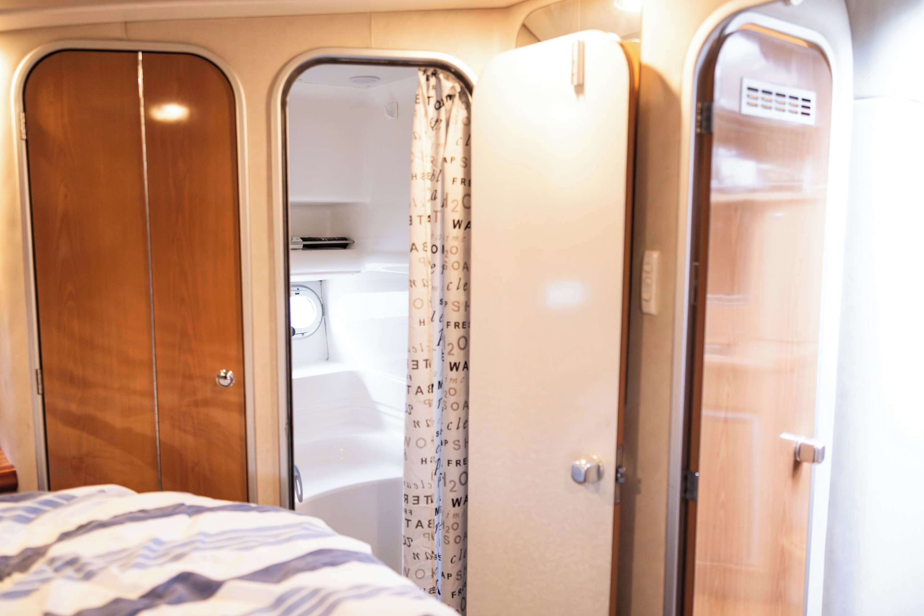 Un espacio interior compacto con una cama, un baño con ducha y un armario.