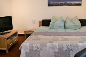 Ein Hotelzimmer mit Bett, Fernseher, Nachttisch und einem Bild an der Wand.