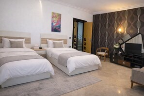 Habitació d'hotel amb dos llits, televisió, una cadira i un mur decoratiu.