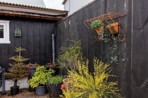 A wooden fence with potted plants and a hanging pot rack.