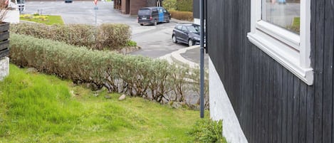 En modern byggnad med ett stort fönster, ett garage och en parkeringsplats med bilar.