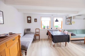 A cozy room with a bed, a dining table, and a sofa. - Traditional Faroese House Near Airport (Sørvágur)