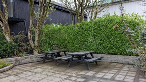 A patio area with picnic tables and a brick floor.