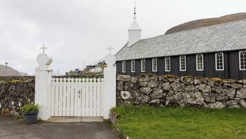 A church with a white fence, stone wall, and a grey roof.