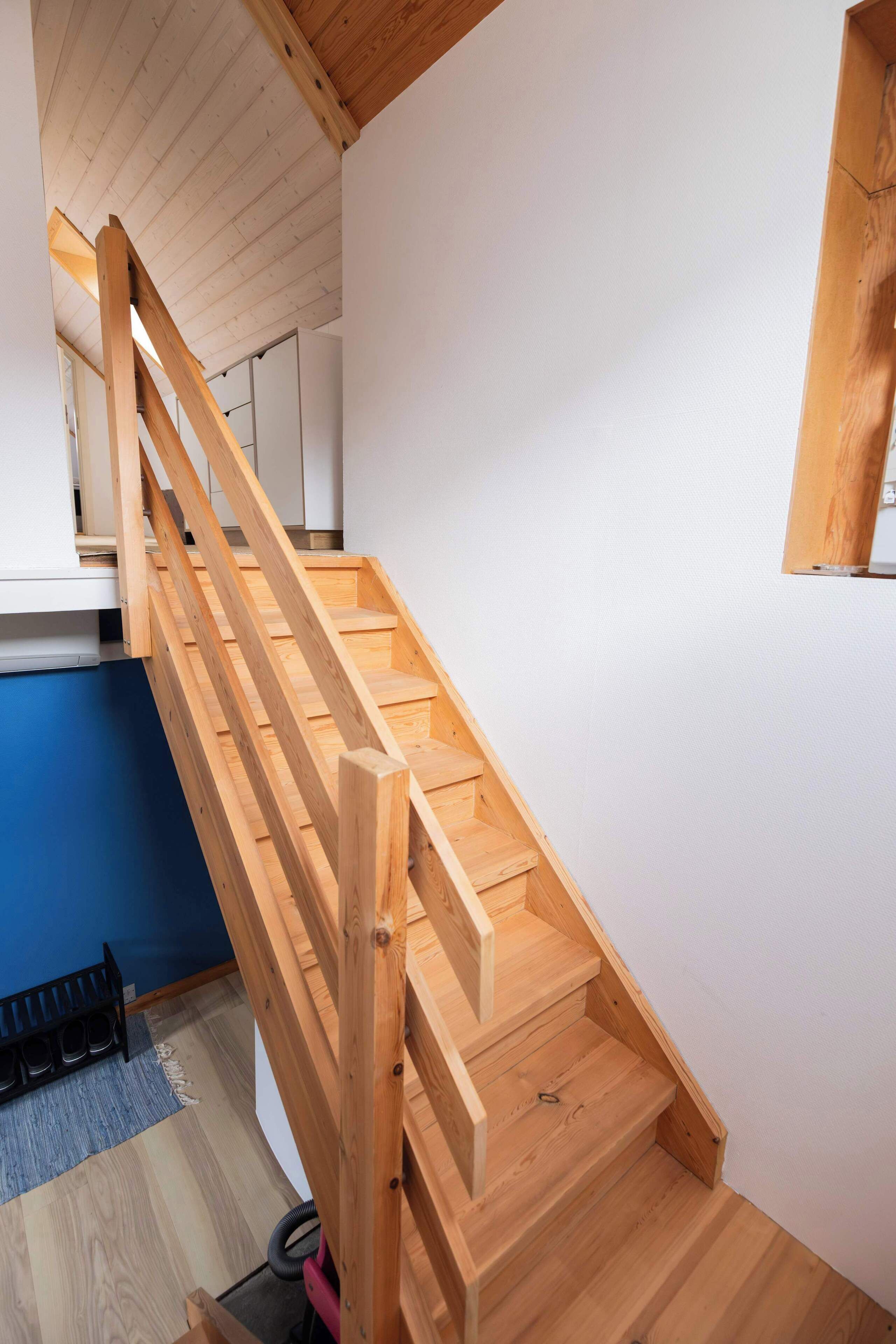 Una escalera de madera con barandilla que conduce a un piso superior.