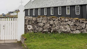 A church with a stone wall and a white fence in front.