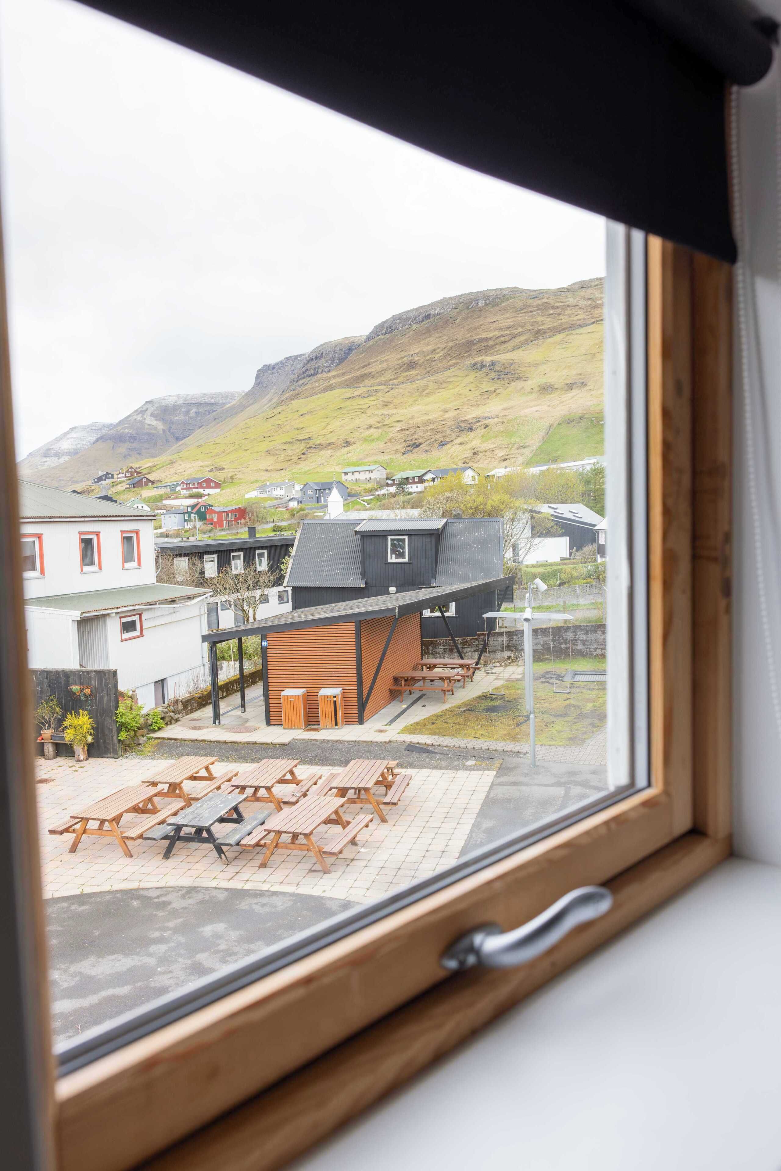 Une vue par la fenêtre sur un quartier résidentiel, avec des maisons, une table de pique-nique et une montagne en arrière-plan.