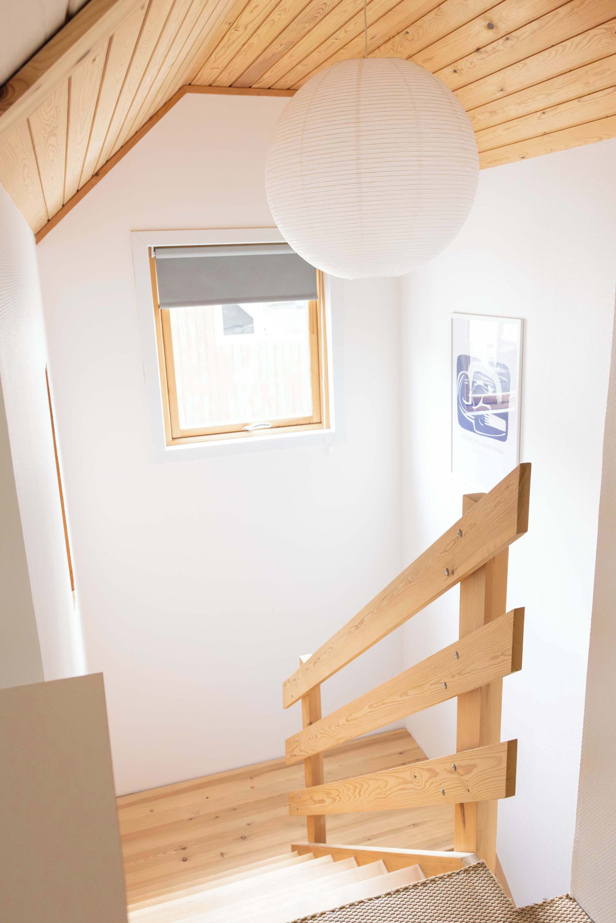 A wooden staircase in a room with a sloped ceiling and a hanging light fixture.