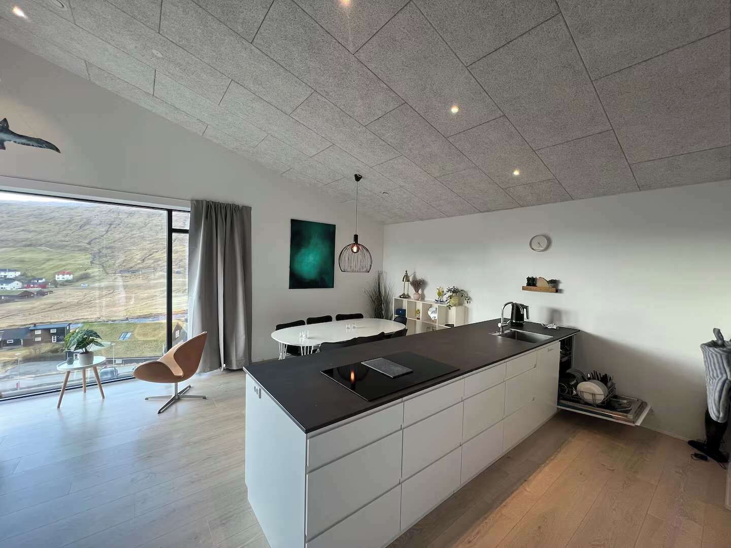 Una cocina moderna con una isla grande, comedor y vistas al campo.