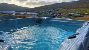 Un bain à remous avec vue sur un petit village et des collines en arrière-plan.