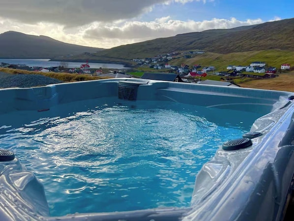 A hot tub with a view of a small village and hills in the background.