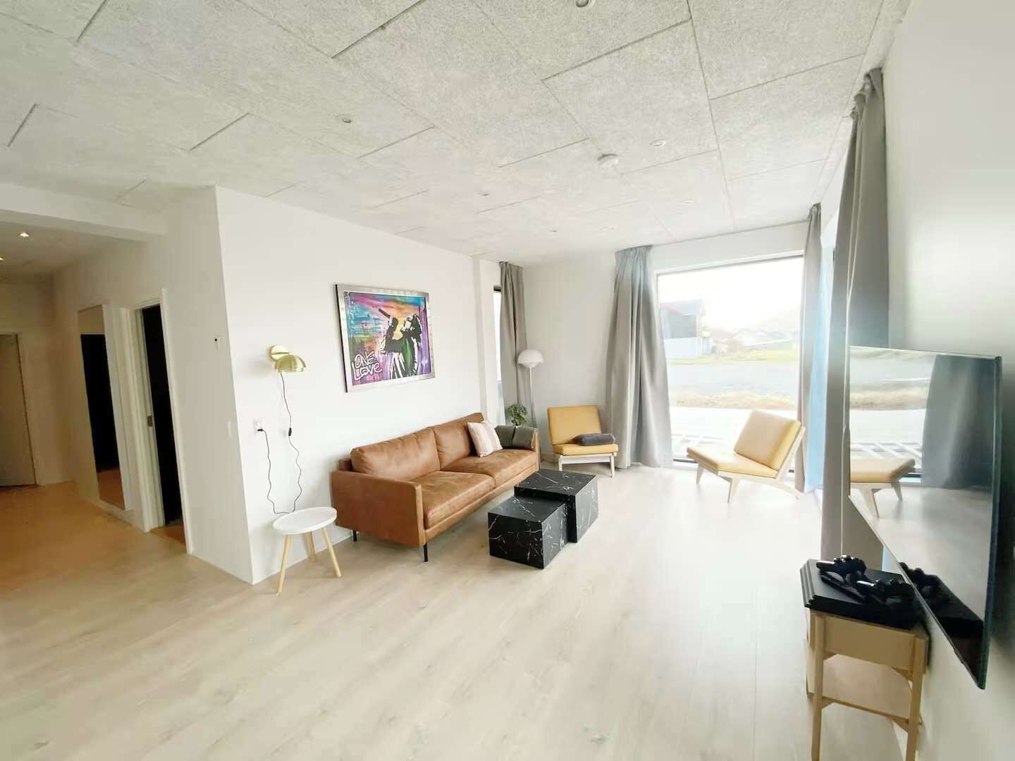 Een moderne woonkamer met een leren bank, een klein rond tafeltje en een flatscreen televisie.