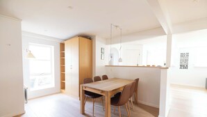 A spacious dining area with a wooden table and chairs, a built-in wooden cabinet, and pendant lighting. - Relaxed Stay with Fjord Views in Hvalvik (Hvalvík)