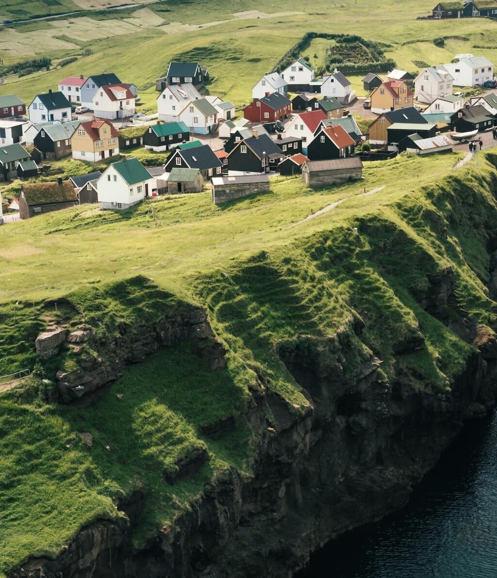 En kystlandsby med huse bygget på grønne skråninger.