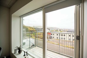 Ein Balkon mit Blick auf eine Stadtansicht, einer Topfpflanze und einem Metallgeländer.