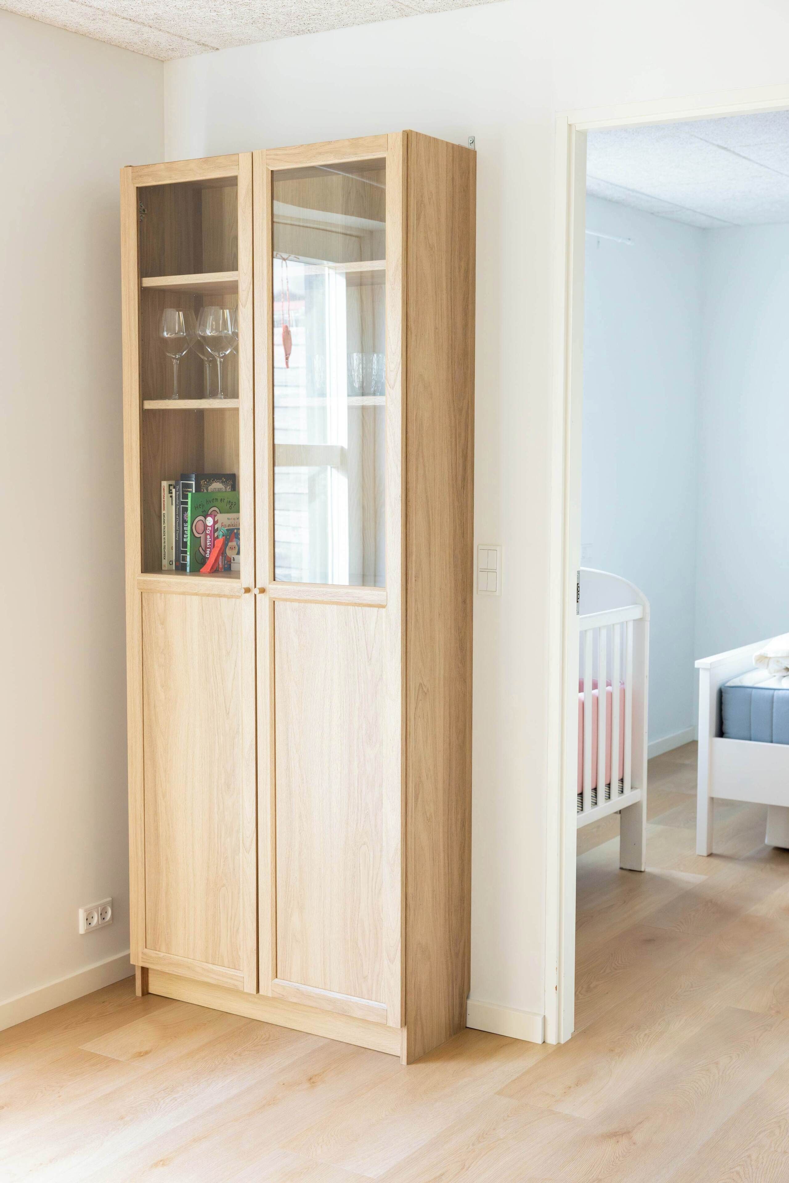 Ein Zimmer mit einem hölzernen Kleiderschrank, einem Babybett und einem weißen Bett.