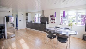A modern kitchen with a dining area, wooden flooring, and a view of the outside.