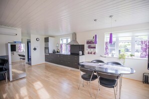 Une cuisine moderne avec un coin repas, un plancher en bois et une vue sur l’extérieur.