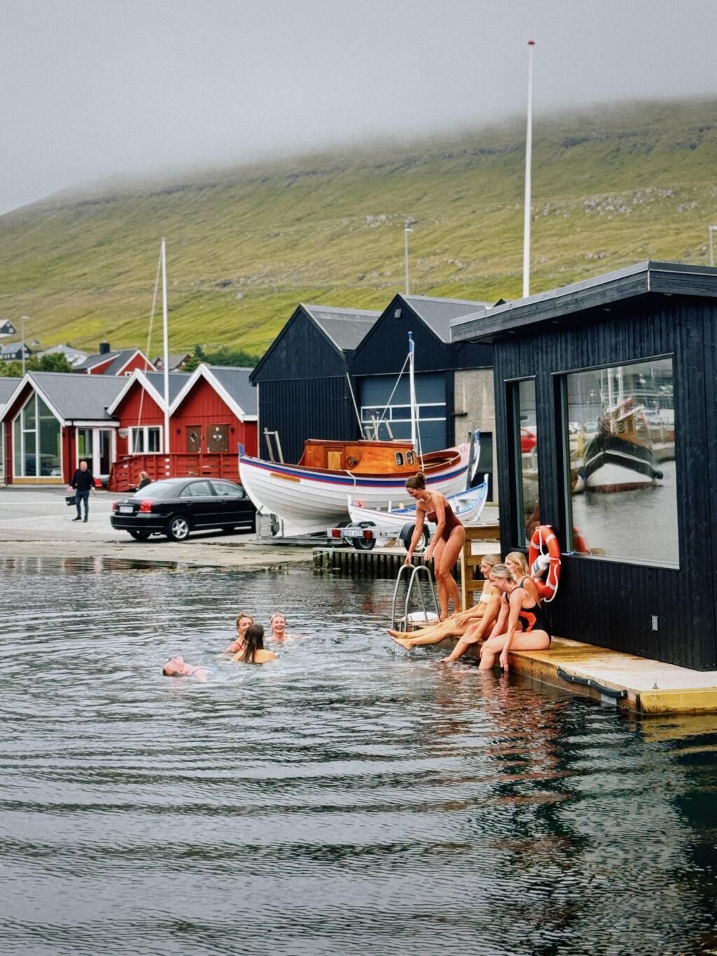 Une scène de bord de mer avec un quai, un petit bâtiment et un bateau.