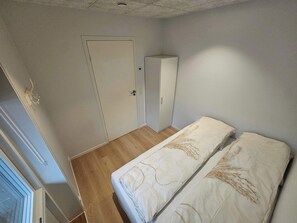 A small bedroom with a single bed, a wardrobe, and a door.