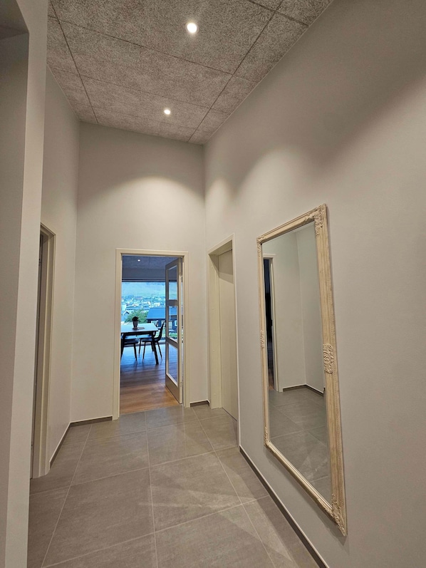 A hallway with a large mirror, a dining area with a table and chairs, and a view through an open door.