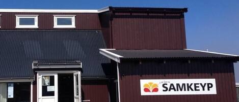 A building with a SAMKEYP sign, a door, and a small attached structure.