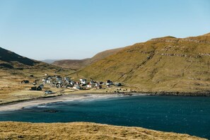Un village côtier avec des maisons construites le long du littoral, entouré de collines.