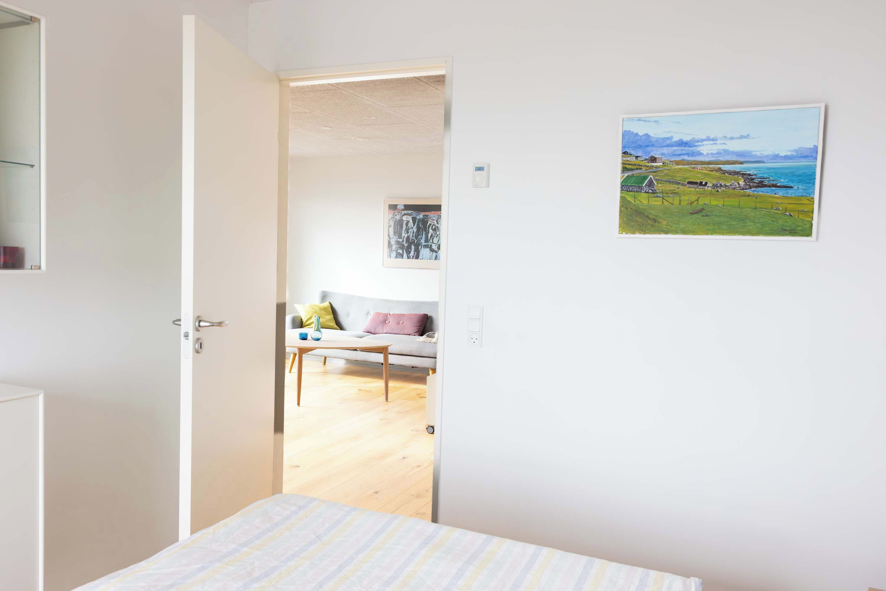 Ein Zimmer mit einem Bett, einem Gemälde, einer Couch und Blick ins Freie.