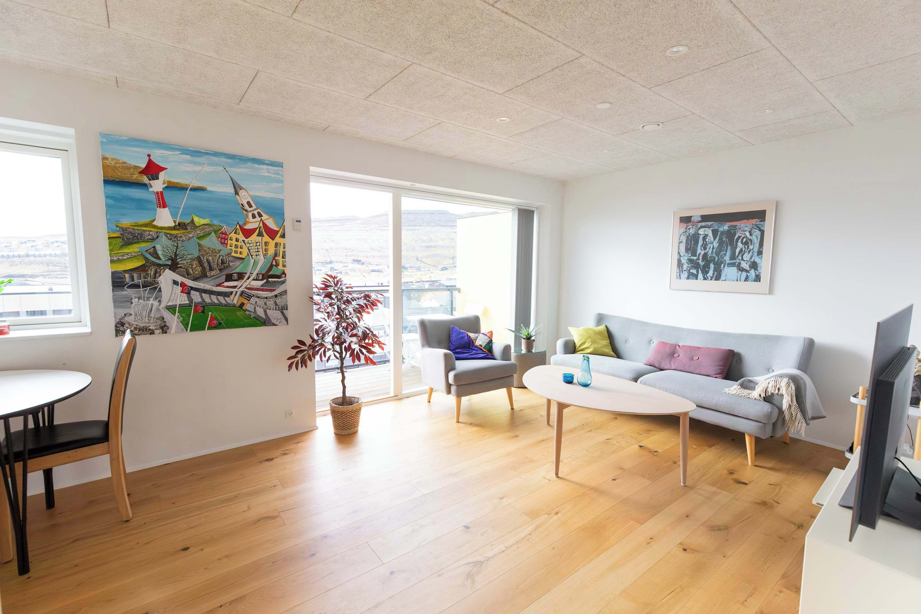 Ein modernes Wohnzimmer mit einer Couch, Sesseln, einem Couchtisch und Kunstwerken an den Wänden.