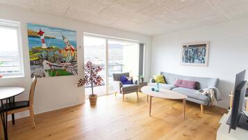 Ein modernes Wohnzimmer mit einer Couch, Sesseln, einem Couchtisch und Kunstwerken an den Wänden.