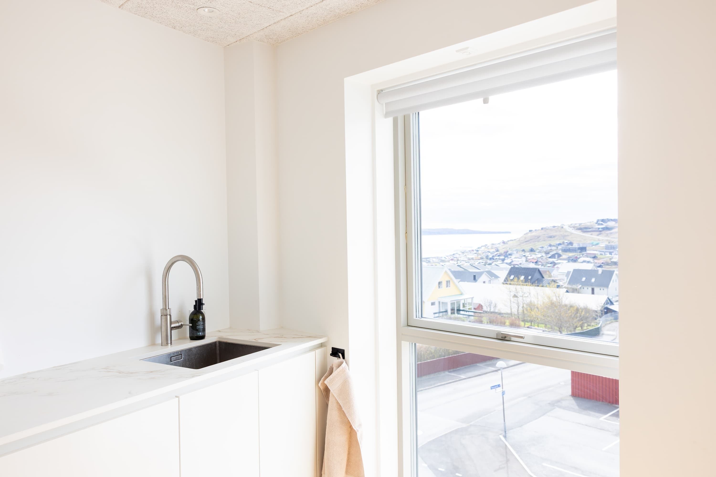 A kitchen with a window, a sink, and a towel hanging on the door.