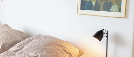A bedroom with a bed, a nightstand, a lamp, and a painting on the wall.