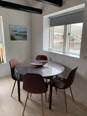 Un comedor con una mesa redonda, cuatro sillas, un cuadro en la pared y una ventana con vistas al paisaje.