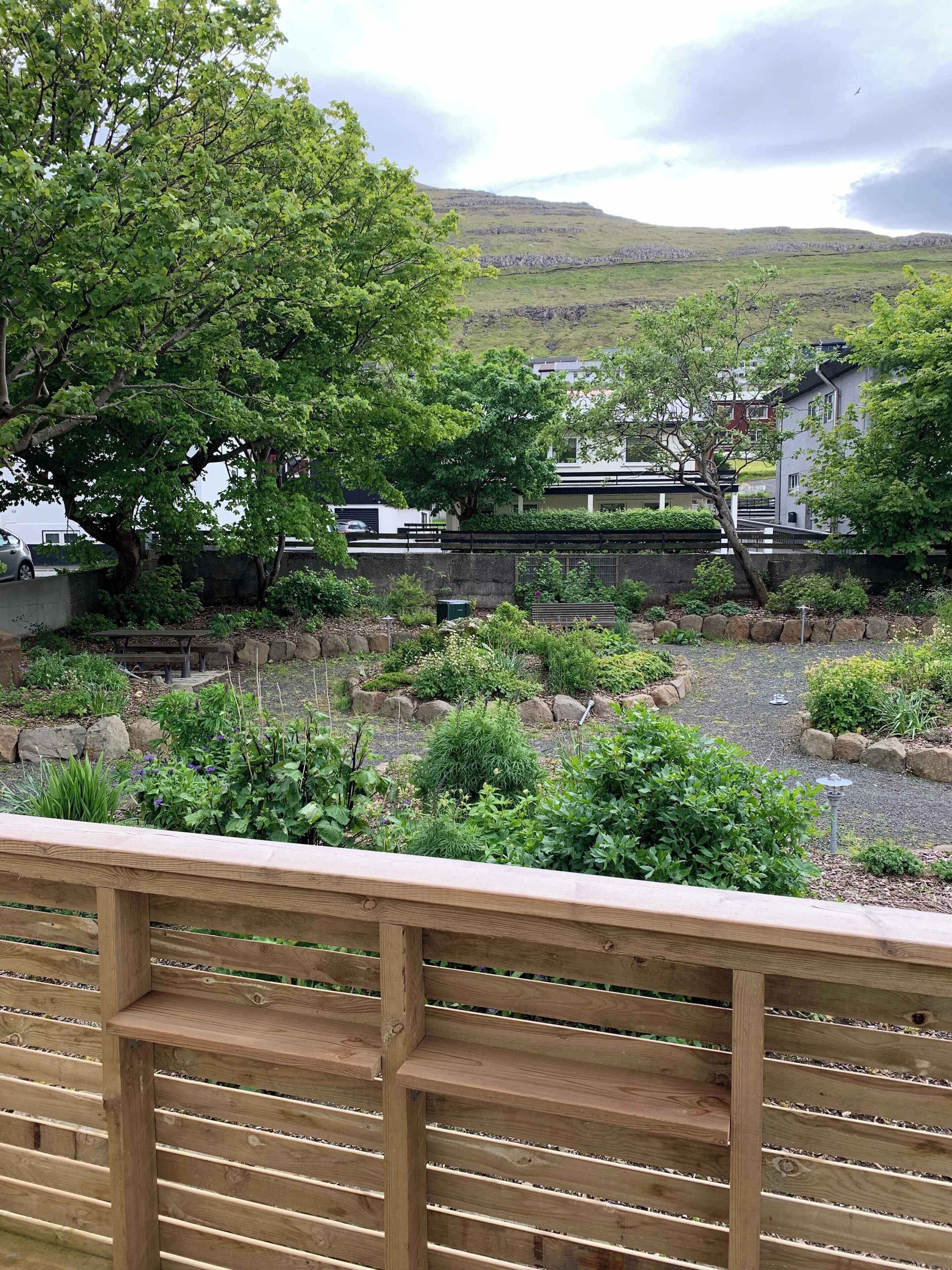 Un jardín con diversas plantas y una terraza de madera.