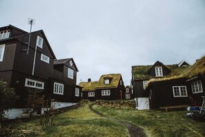 A row of traditional houses with thatched roofs and a narrow path leading through them. - Light, Calm and Modern Corner Apartment (Argir)