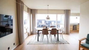 Un salon moderne avec un coin repas, de grandes fenêtres et une vue sur la ville.