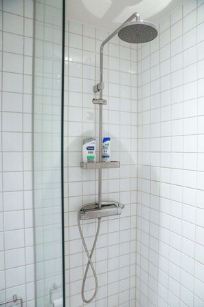 A shower with a handheld showerhead, a handheld shower attachment, and a soap dispenser on a shelf. - Light, Calm and Modern Corner Apartment (Argir)