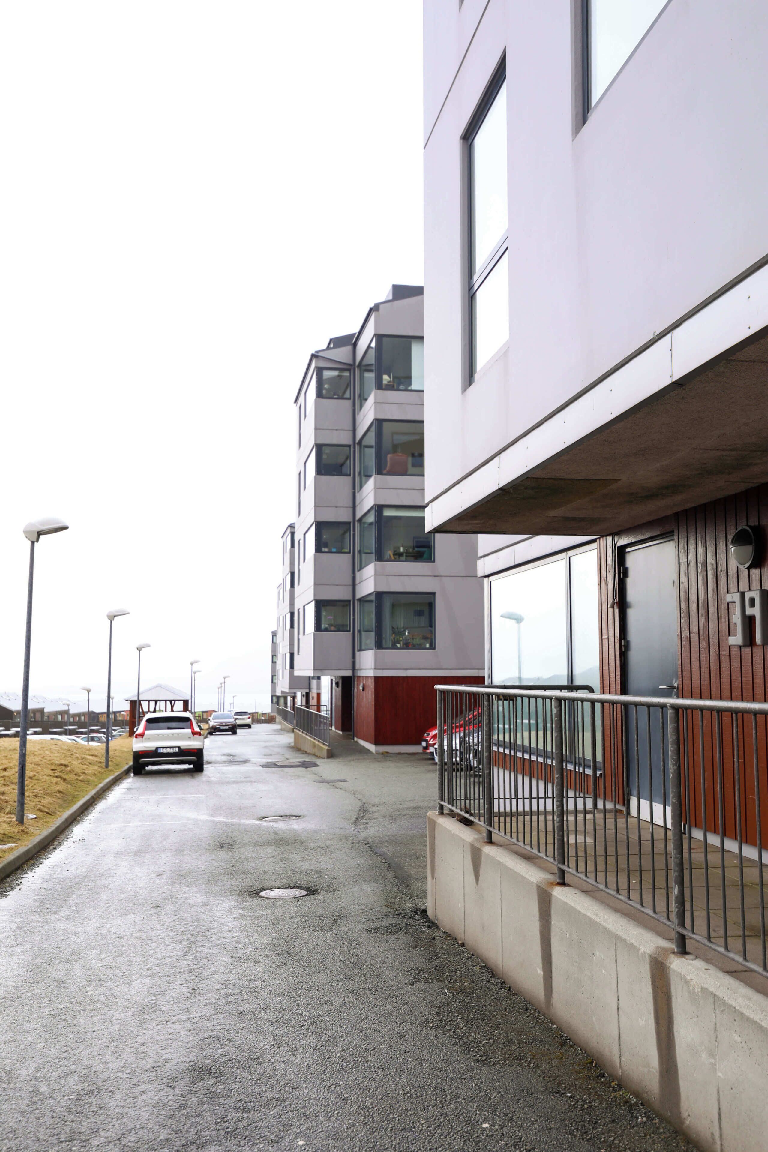 Um edifício moderno com fachada plana, grandes janelas e entrada protegida por portão.